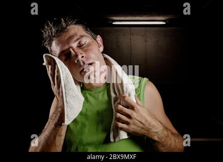 portrait sombre et edgy de jeune homme de sport fatigué et épuisé avec bouteille d'eau de refroidissement après l'entraînement de fitness dur au club de gym transpiration séchage Banque D'Images