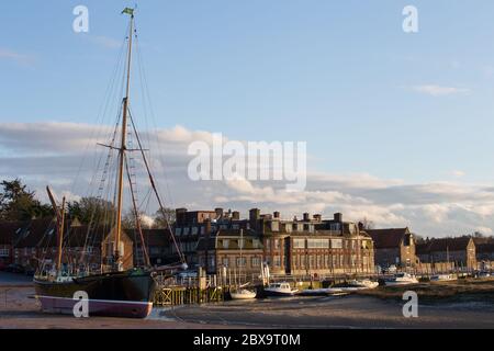 L'hôtel Blakeney et le front de mer, Blakeney, avec la barge à voile 'Juno' amarrée à marée basse sur Agar Creek, Blakeney, Norfolk, Angleterre Banque D'Images