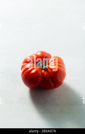 une tomate rouge sur la table. lumière de derrière. coeur rouge Banque D'Images