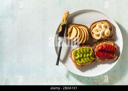 divers sandwiches avec beurre d'arachide et fraises, céleri, banane et pomme sur une assiette sur la table. petit déjeuner parfait Banque D'Images