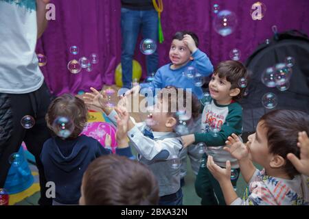 Joli petit garçon attrapant des bulles de savon . Petit garçon blond jouant avec des bulles de savon . Enfants à la fête. Des bulles de savon apparaissent. Fête d'enfants. À Banque D'Images