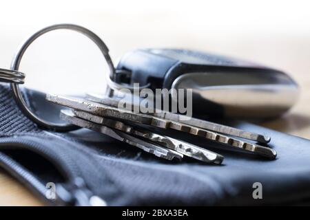 Un bouquet de clés de porte, maison et voiture sur un anneau en métal avec une couverture en cuir sur une table Banque D'Images