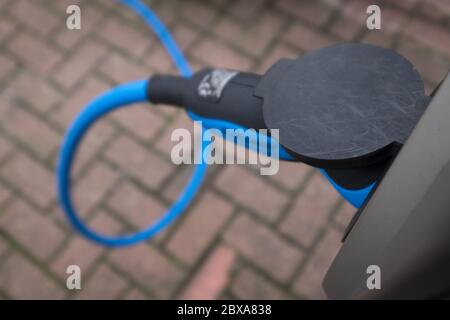 Gros plan sur la prise d'alimentation d'une station de charge de voiture électrique. L'alimentation électrique est branchée dans une voiture électrique en cours de charge. Banque D'Images