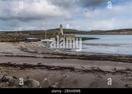 Plage de sable avec yachts au sol et jetée avec clocher Thomas Telford à Port Logan, Dumfries & Galloway, Écosse, Royaume-Uni. Banque D'Images