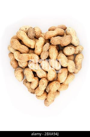Coeur en forme de bio dans la coquille arachides tas sur fond blanc Banque D'Images