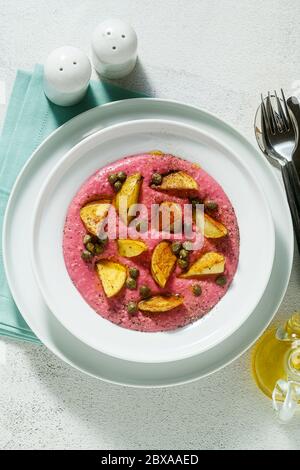 plat d'été avec houmous roses à base de haricots cannellini et betteraves avec pommes de terre frites et câpres dans une assiette sur la table Banque D'Images