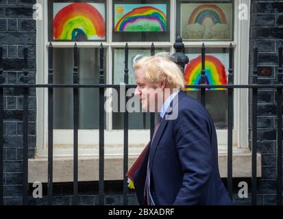 Le Premier ministre, Boris Johnson, passe devant des photos arc-en-ciel dessinées par des enfants pour montrer son soutien aux travailleurs du NHS qui luttent contre la pandémie du coronavirus. Banque D'Images