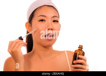 Portrait jeune femme asiatique coréenne belle et heureuse appliquant des soins de la peau prévention des rides traitement de sérum ou vieillissement produit de beauté sur son visage en faire Banque D'Images