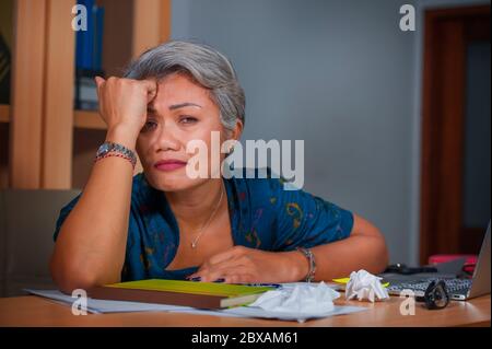 Portrait expressif d'une femme asiatique attirante, stressée et surtravaillée travaillant au bureau, ordinateur portable, en stress, frustrée et bouleversée Banque D'Images