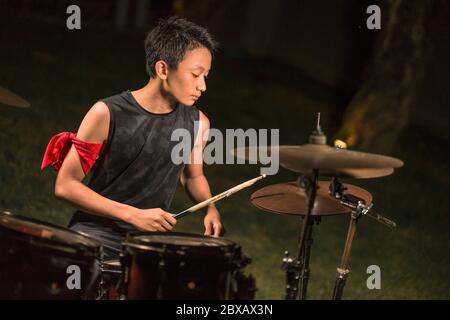 Asiatique américain mixte adolescent jouant des tambours à la maison jardin . cool et beau jeune garçon pratiquant sur le kit de tambour répéter passionné dans badass rock b. Banque D'Images