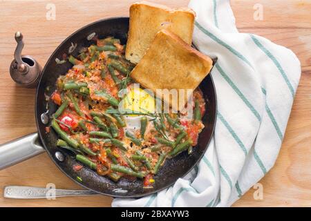 Shakshuka de tomate aux haricots verts, une paire de toasts dans une casserole métallique Banque D'Images