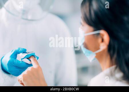 Travailleur médical vérifiant l'oxygène du sang du patient coronavirus Banque D'Images