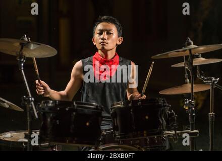 Asiatique américain mixte adolescent jouant des tambours à la maison jardin . cool et beau jeune garçon pratiquant sur le kit de tambour répéter passionné dans badass rock b. Banque D'Images