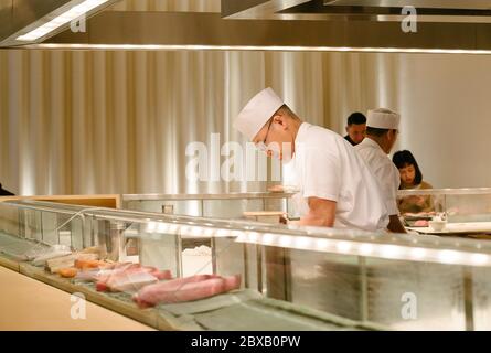 Chef de sushi travaillant derrière le bar à sushis Banque D'Images