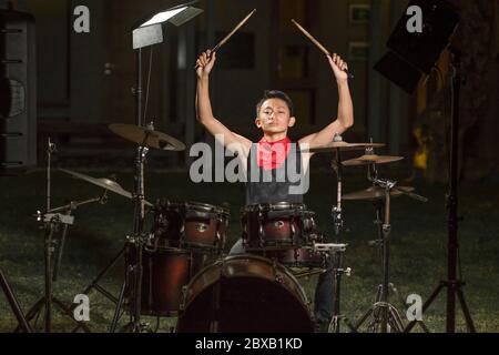 Asiatique américain mixte adolescent jouant des tambours à la maison jardin . cool et beau jeune garçon pratiquant sur le kit de tambour répéter passionné dans badass rock b. Banque D'Images