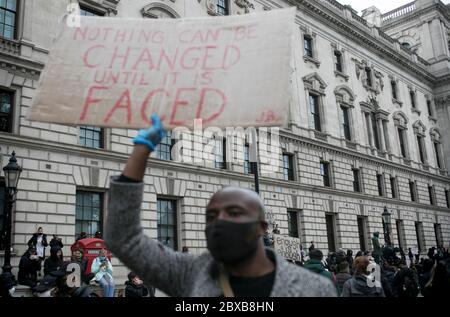 Un manifestant passe devant les bâtiments institutionnels du centre de Londres et tient une pancarte contre le racisme systémique au Royaume-Uni. Banque D'Images