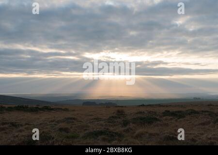 Vue de Dartmoor vers la côte du Sud Devon avec des rayons crépusculaires roses et dorés (échelle de Jacob) de lumière du soleil se propageant sur le paysage t Banque D'Images