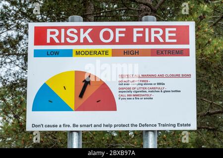 Panneau d'avertissement de risque d'incendie avec flèche pointant vers un risque élevé, avis sur le domaine d'entraînement de la défense (terre MOD, heathland), Hankley Common, Surrey, Royaume-Uni Banque D'Images