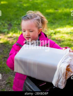 Fille pré-école vider bac de compost pendant le verrouillage, fille portant un manteau rose faisant du compostage, enseigner la fille pré-école au sujet du compost Banque D'Images