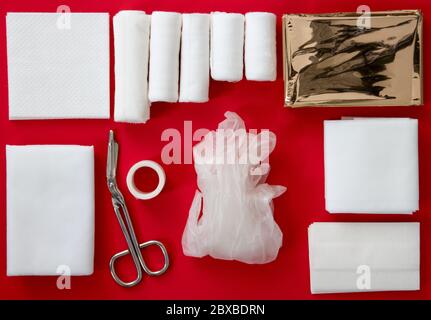 Intérieur d'une trousse de premiers soins isolée sur fond rouge Banque D'Images