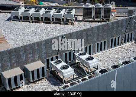 Équipement de climatiseurs sur un toit en gravier d'un bâtiment industriel. Machines à ventilateur HVAC. Banque D'Images