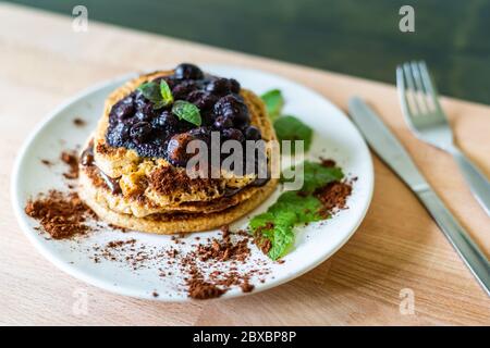 Délicieuses crêpes à l'avoine américaine avec toping au chocolat maison, bleuets cuits et feuilles de menthe fraîche. Une cuisine saine Banque D'Images