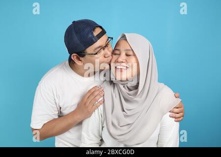 Portait de heureux couple asiatique musulman souriant, mari et femme embrassant et embrassant plein d'amour, concept de famille Banque D'Images