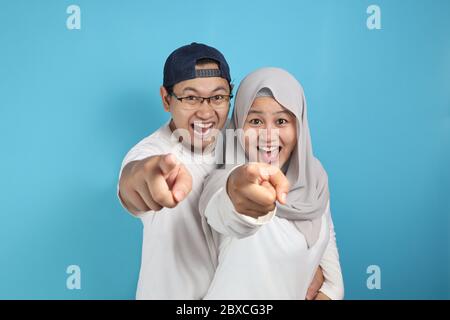 Portait de heureux asiatique couple musulman souriant et pointant vers l'appareil photo, mari et femme embrassant plein d'amour, concept de famille Banque D'Images