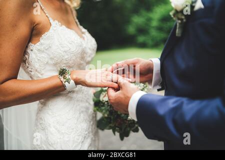 Vue latérale des mains des mariés. Des jeunes mariés se tiennent à la main lors de la cérémonie de mariage. Mariage couple mettre des anneaux l'un sur l'autre. Concept de mariage. Banque D'Images