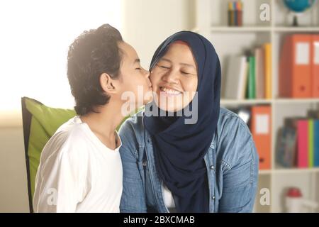 Une mère musulmane asiatique heureuse portant le hijab embrasse son petit garçon, une mère célibataire et un enfant étant une famille heureuse ensemble, concept de maternité Banque D'Images