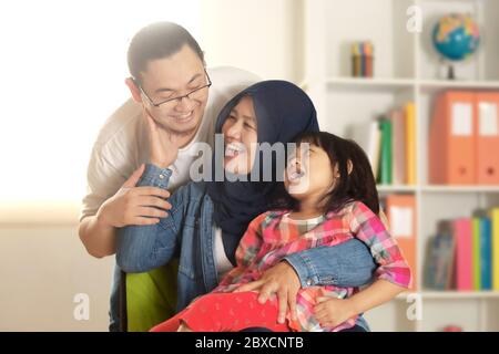 Les parents musulmans et la petite fille de baggy, le père et la mère avec leur fille, souriant heureux joue ensemble dans leur maison Banque D'Images