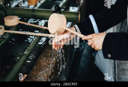 Fille se lavant les mains au temple japonais Banque D'Images