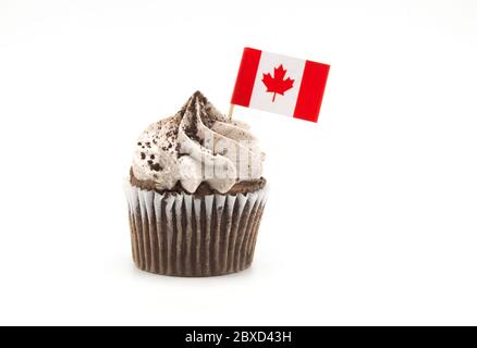 Un gâteau au chocolat et à la crème avec un petit drapeau de cure-dent de la feuille d'érable du Canada coincé dans lui, isolé sur blanc Banque D'Images