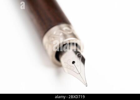 Gros plan du corps en bois et de la pointe d'écriture d'un stylo-plume classique sur fond blanc Uni. Banque D'Images