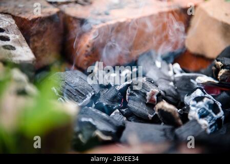 Les empères d'un feu mort fumage dans la clôture en briques. Le feu après le barbecue. Banque D'Images