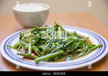 Vue de dessus de 'Pad Pak Boong', un plat traditionnel thaïlandais : légumes 'Morning Glory' sautés (Ipomoea aquatica) servis dans une assiette blanche Banque D'Images