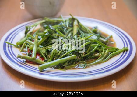 Vue de dessus de 'Pad Pak Boong', un plat traditionnel thaïlandais : légumes 'Morning Glory' sautés (Ipomoea aquatica) servis dans une assiette blanche Banque D'Images