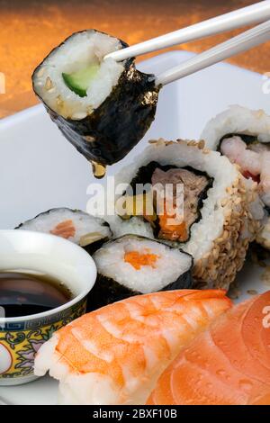 Le sushi est un plat japonais composé de petites boules ou de petits rouleaux de riz froid au vinaigre, servis avec une garniture de légumes, d'œufs ou de fruits de mer crus. Banque D'Images