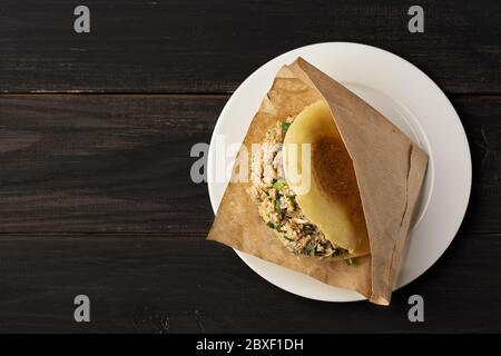 Roujiamo est un hamburger chinois populaire. Restauration rapide. Sandwich maison dans un emballage papier sur une table en bois noir. Vue de dessus. Copier l'espace. Pose à plat. Banque D'Images
