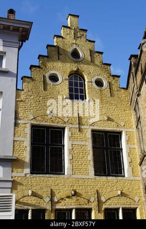 Façade d'une maison jaune avec un toit de sable à l'étape dans la vieille ville de Bruges Banque D'Images
