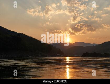 Coucher de soleil lors d'une promenade en bateau sur le Mékong au Laos. Visite en ferry sur le Mékong dans la région de Luang Prabang. Falaises et plages incroyables en arrière-plan Banque D'Images