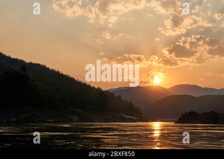 Coucher de soleil lors d'une promenade en bateau sur le Mékong au Laos. Visite en ferry sur le Mékong dans la région de Luang Prabang. Falaises et plages incroyables en arrière-plan Banque D'Images