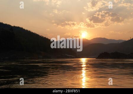 Coucher de soleil lors d'une promenade en bateau sur le Mékong au Laos. Visite en ferry sur le Mékong dans la région de Luang Prabang. Falaises et plages incroyables en arrière-plan Banque D'Images