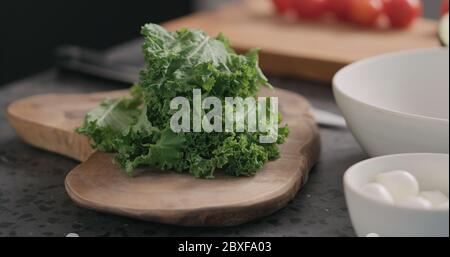 homme déchirant les feuilles de chou frisé pour les rendre plus tendres pour la salade vue latérale sur la cuisine Banque D'Images