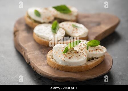 Bruschetta à la mozzarella, basilic et pesto sur panneau de bois d'olive Banque D'Images