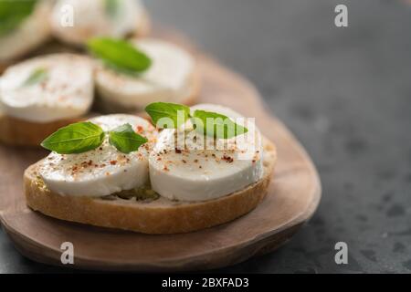 Bruschetta à la mozzarella, basilic et pesto sur panneau de bois d'olive Banque D'Images