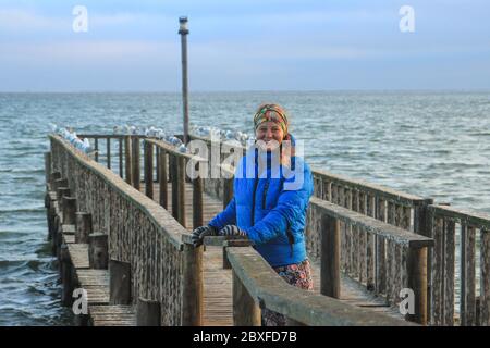 Jeune fille de race rouge caucasienne routard sur un quai dans la ville de Walvis Bay (Namibie, Afrique) sur fond de l'océan Atlantique Banque D'Images