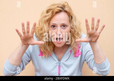 Une femme blanche fait une expression drôle en levant ses mains près de son visage Banque D'Images