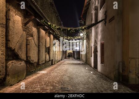 Vue sur le passage de Sainte-Catherine à Tallinn la nuit. Les pierres tombales sont visibles sur le côté gauche. Banque D'Images