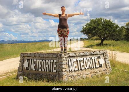 La météorite la plus importante au monde à Grootfontein, en Namibie. White Girl touriste se tient sur le signe Banque D'Images